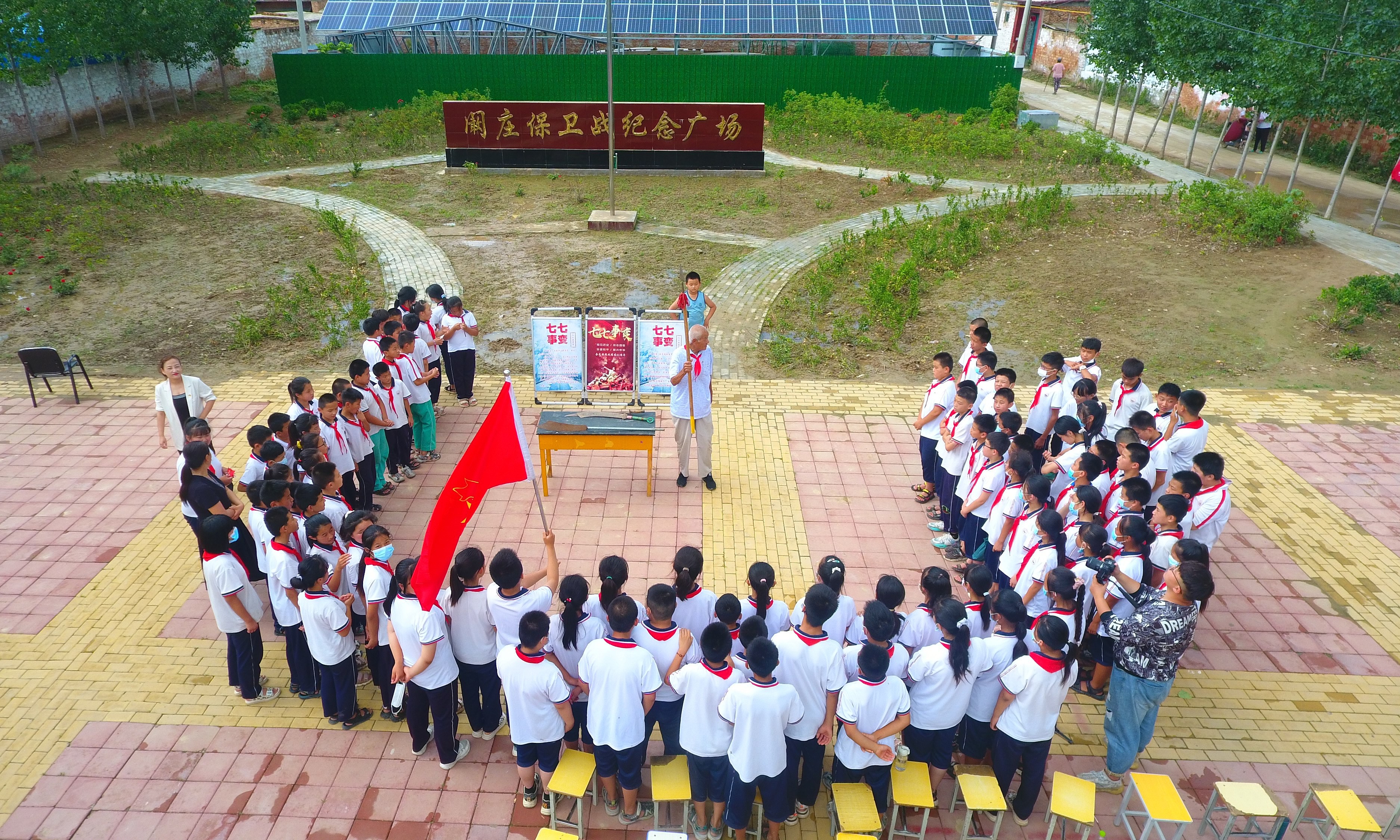 2022年7月6日，山東省聊城市，在茌平區(qū)菜屯鎮(zhèn)闞莊村的闞莊保衛(wèi)戰(zhàn)紀念廣場，闞莊保衛(wèi)戰(zhàn)親歷者王光木老人，為小學生們講述抗戰(zhàn)故事，展示大刀、長矛。